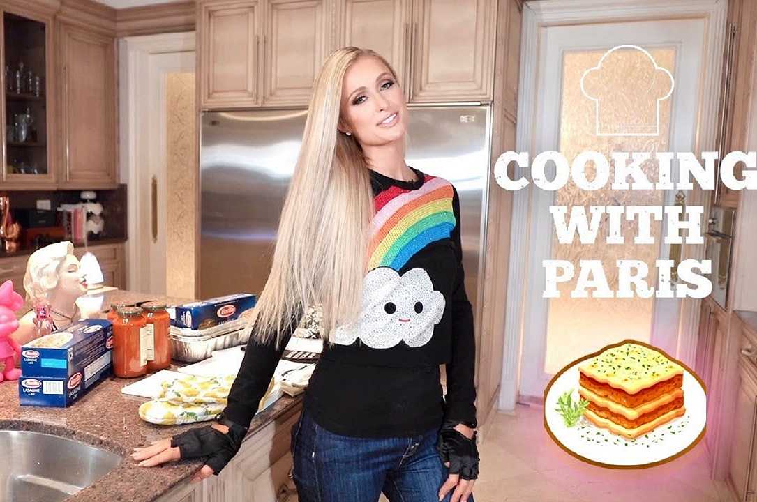 Paris Hilton ai fornelli: lasagne con il cane in braccio, è polemica social