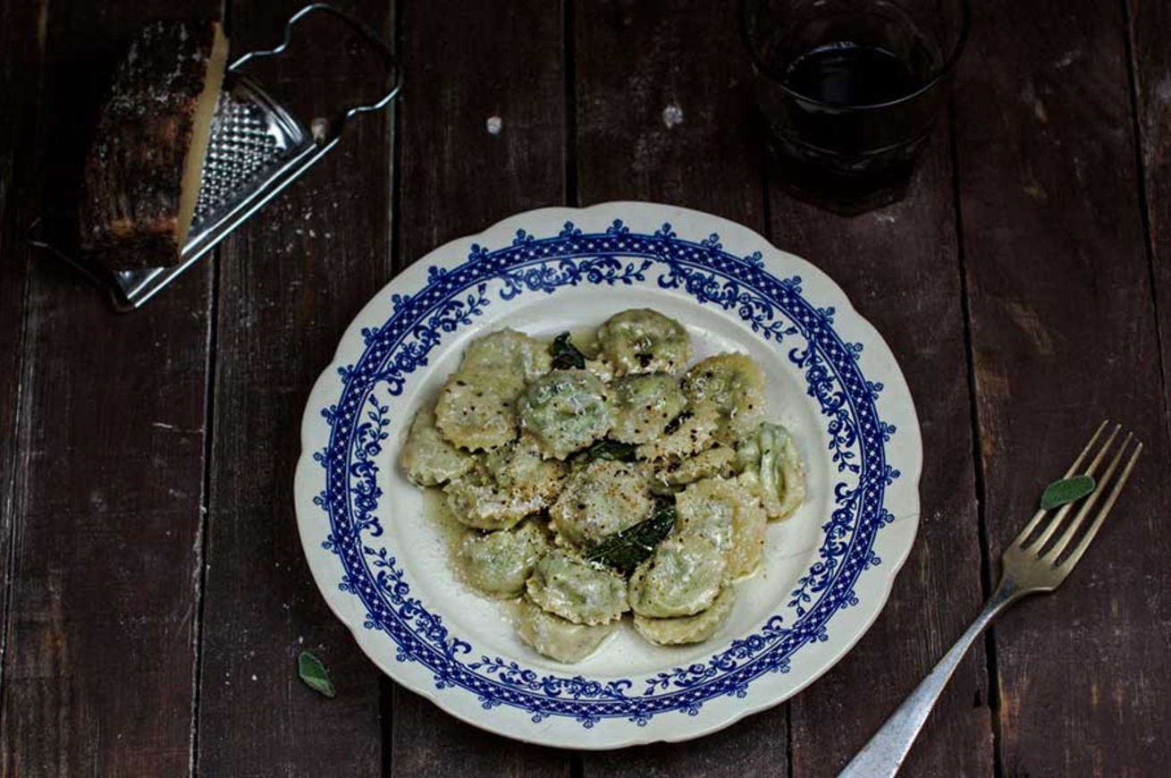 ravioli agli spinaci in un piatto con formaggio e salvia