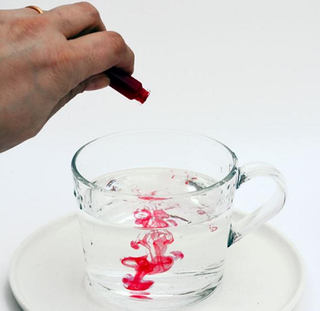 tazza con acqua a cui sono aggiunte alcune gocce di colorante rosso