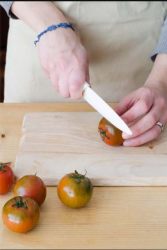 mani che tagliano la calotta ai pomodori