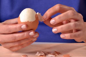 mani che sbucciano un uovo