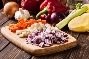 patate carote e cipolle a pezzi su un tagliere