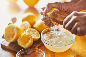 mani che spremono il limone in una ciotola