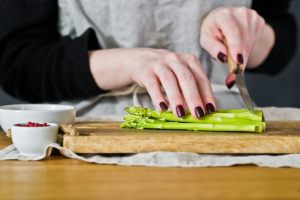 mani che tagliano la parte coriacea degli asparagi