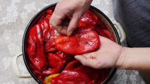 mani che sbucciano dei peperoni al forno