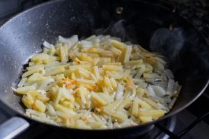patate e cipolle in padella che rosolano