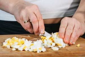 mani che tagliano le uova sode a cubetti