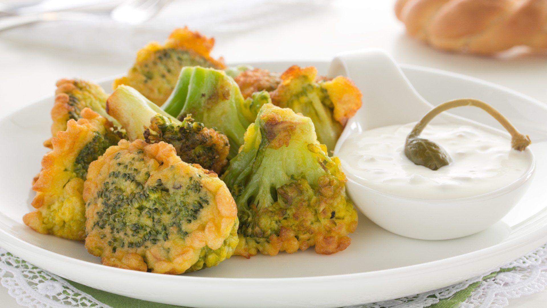 broccoli impastellati su un piatto con salsa bianca e capperi