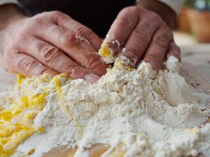 mani che impastano farina e tuorlo d'uovo