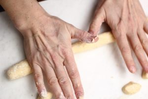 mani che realizzano un filoncino di pasta per i krumiri