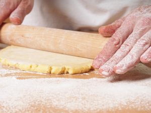 mani che stendono la pasta frolla con il mattarello