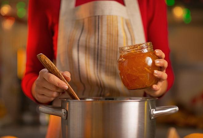 donna che invasa la marmellata di arance amare senza zucchero in un vasetto di vetro