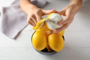 mani che prelevano la scorza del limone col pelapatate