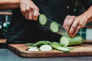 mani che tagliano le zucchine a fette sottili
