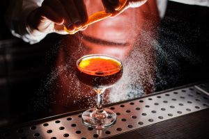 barman che aggiunge gli oli essenziali di arancia