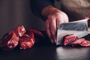 mani che tagliano la carne di cinghiale