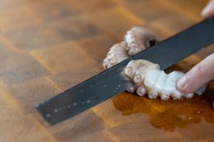 coltello che taglia il tentacolo di polpo