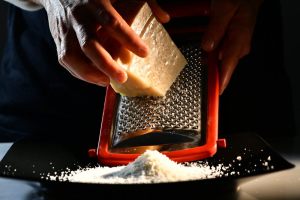 mani che grattugiano il Parmigiano
