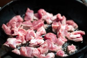 cubetti di carne che rosolano in padella