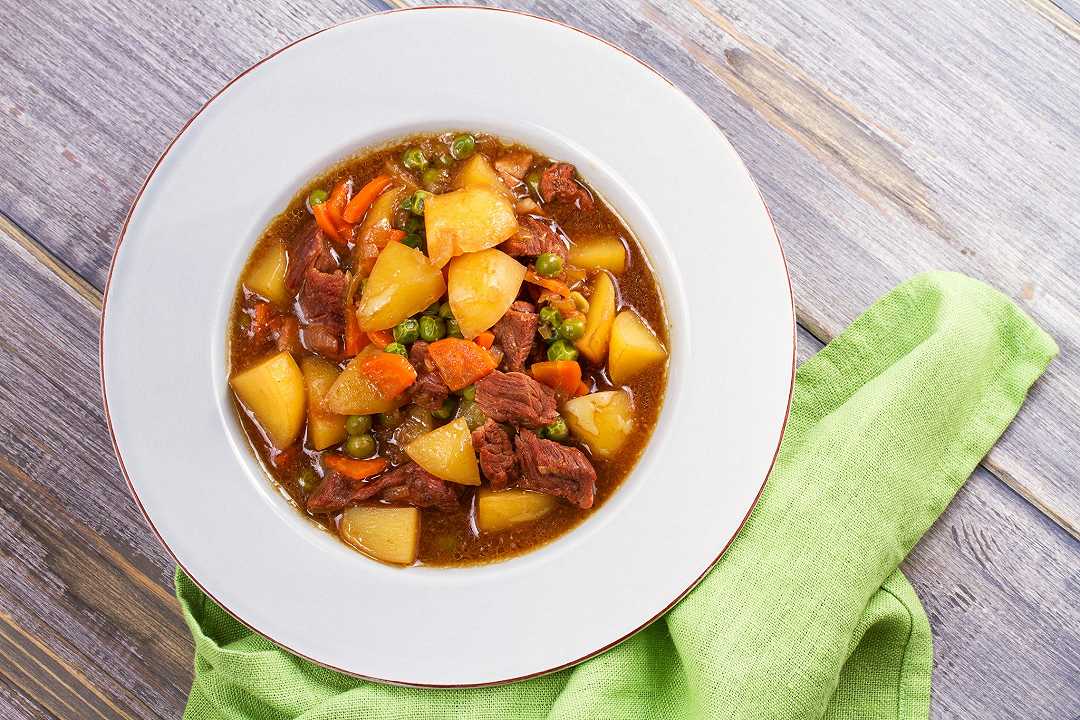 Spezzatino con piselli e patate, la ricetta con il sugo denso e aromatico