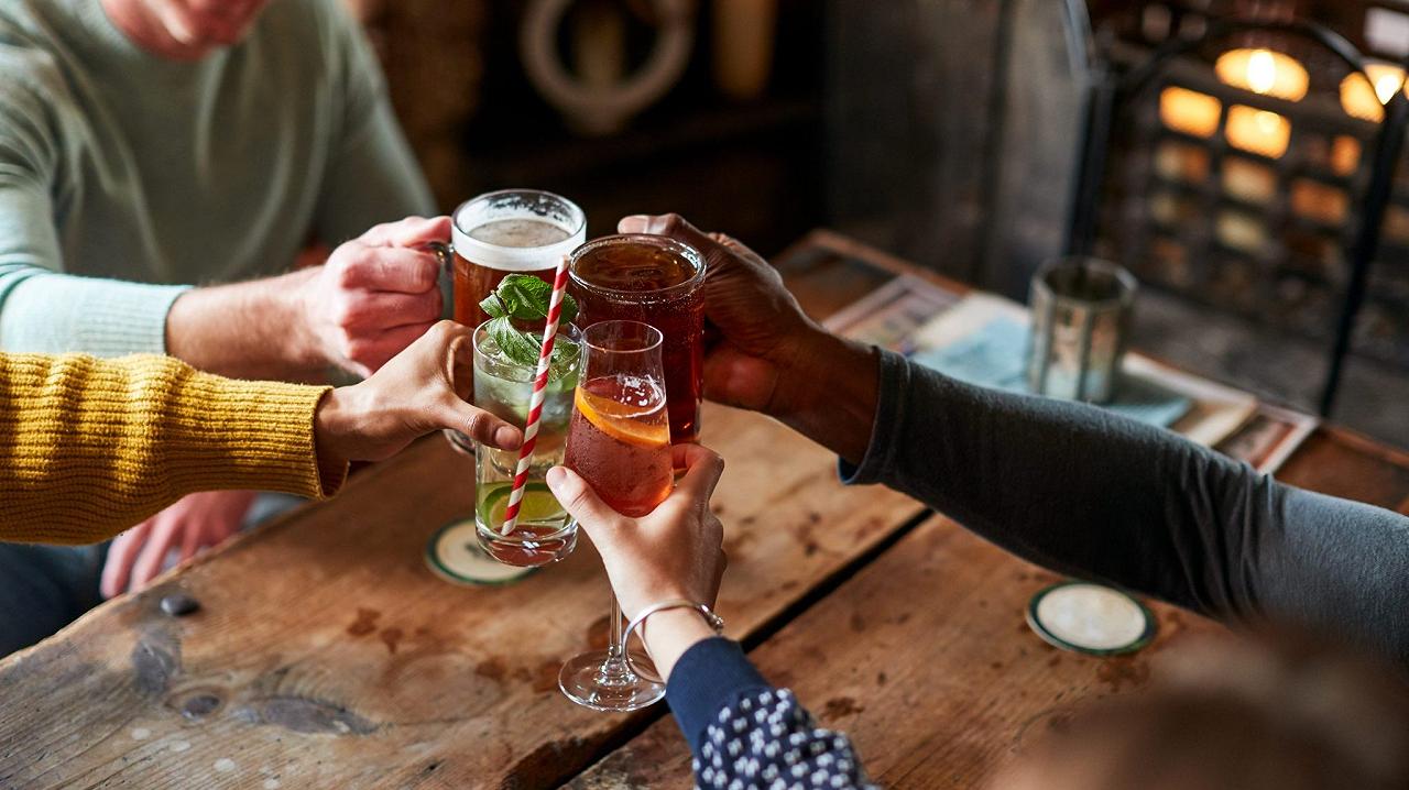 Una pinta di birra analcolica appena spillata sul bancone di legno di un pub inglese, con il banco del bar sfocato sullo sfondo